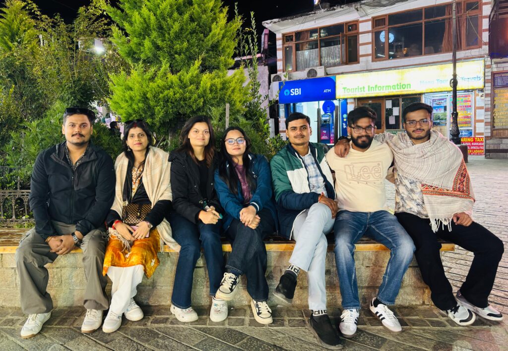 Plan a group trip with friends: seven Yaarana Safar travellers sitting together on an evening street in the hills